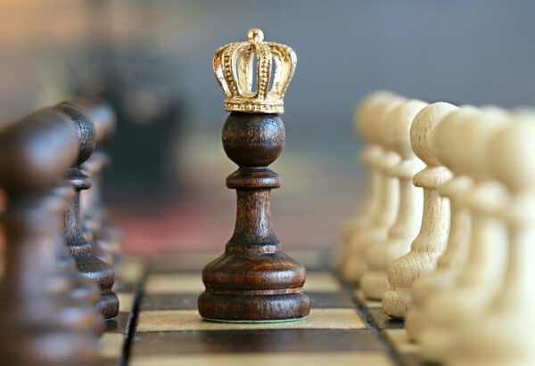 A brown pawn with a crown stands prominently on a chessboard, symbolizing critical thinking.