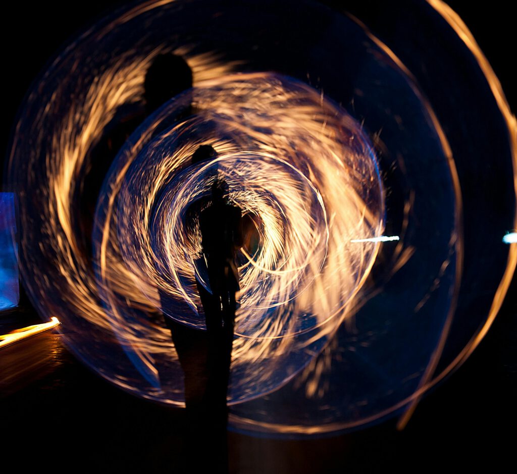 Mesmerizing long exposure shot of fire spinning and silhouette at night.