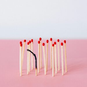 Artistic representation of burnout with matchsticks on a pink surface in a studio setting.